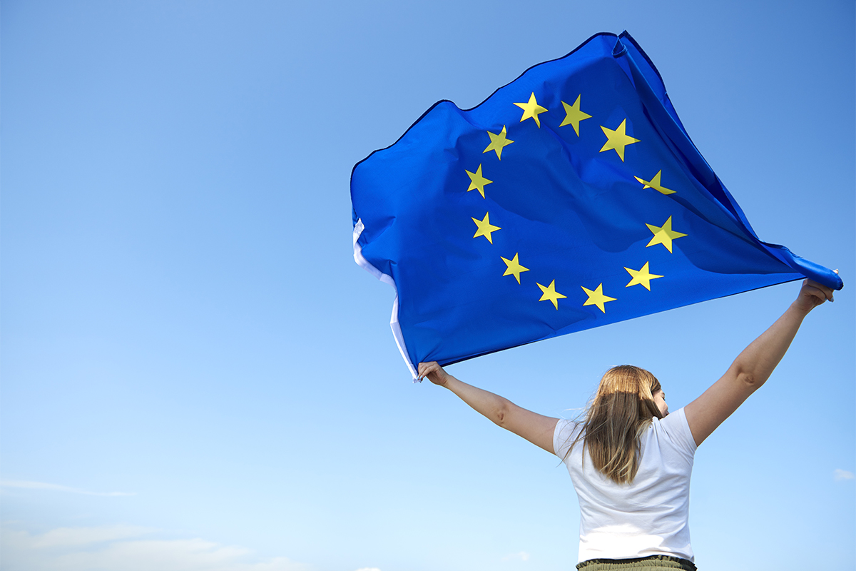 Rear view of young woman waving the European Union flag